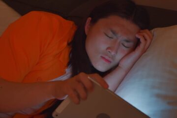 man using a tablet while laying on the bed